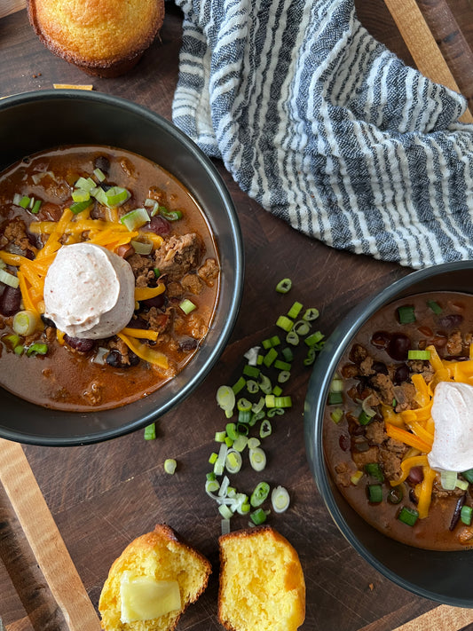 Close-up of a steaming bowl of Tex-Mex turkey chili, garnished with sour cream and green onions