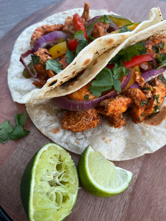 Close-up of sheet pan chicken fajitas with bell peppers, onions, and grilled chicken, served with warm tortillas